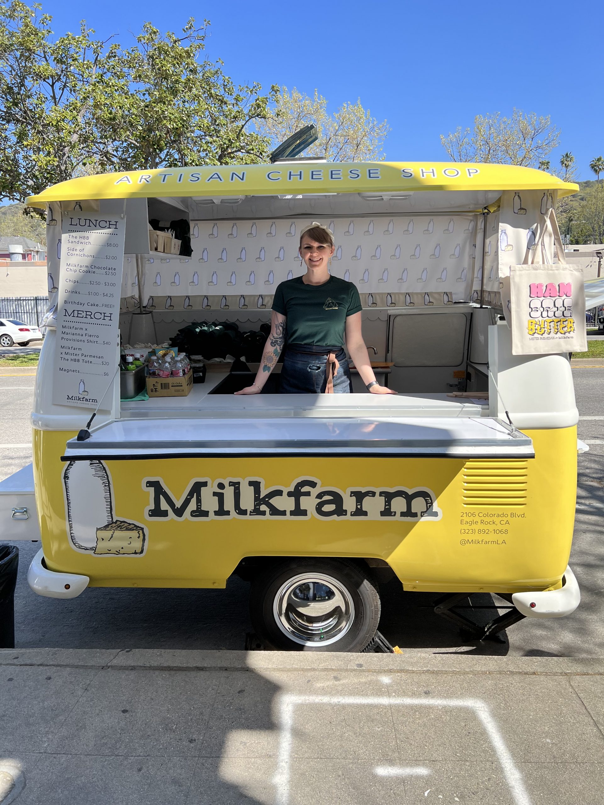 Alyssa Trulson standing inside of our Milkfarm trailer that is yellow with milkfarm bottle and cheese patterned curtains.