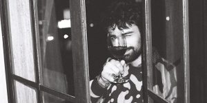 Sam Holding a class of wine looking through a window.